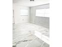 Bright bedroom with modern white and gold marble-patterned tile flooring and natural light at 6366 Forecastle Ct, Orlando, FL 32807