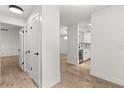 Bright hallway featuring white walls, wood-look floors, and access to the kitchen at 745 Ashley Ln, Orlando, FL 32825
