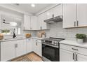 Modern kitchen featuring white cabinets, stainless steel appliances, and a stylish backsplash at 745 Ashley Ln, Orlando, FL 32825