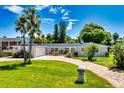 Inviting single-story home showcasing a lush front lawn, brick driveway, and mature palm trees at 105 John Anderson Dr, Ormond Beach, FL 32176