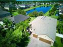 Aerial view of a house with a brick driveway and a beautiful pond nearby, surrounded by lush greenery at 12832 Sawgrass Pine Cir, Orlando, FL 32824