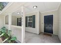 Charming front porch with white columns and railings, leading to a dark front door with sidelights at 15888 Ne 152Nd Ave, Fort Mc Coy, FL 32134