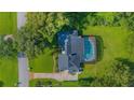 An overhead shot of the home with a screened-in pool, lush lawn, and mature trees at 3160 Whisper Wind Dr, St Cloud, FL 34771