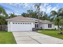 Inviting home featuring a two-car garage, solar panels, and lush green lawn at 705 Sunburst Cove Ln, Winter Garden, FL 34787