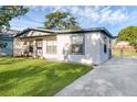 Inviting single-level home showcasing a white exterior, gray trim, and a freshly poured concrete driveway at 7612 Pomelo Dr, Orlando, FL 32819