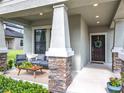 Charming front porch with stone-clad columns, stylish seating, and a welcoming entrance with a wreath-adorned front door at 8030 John Hancock Dr, Winter Garden, FL 34787