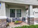 Inviting front porch with stone-clad columns, comfortable seating, and views of the well-maintained front yard and neighborhood at 8030 John Hancock Dr, Winter Garden, FL 34787