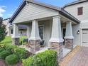 Inviting front porch featuring stone-clad columns, modern furniture, and lush landscaping perfect for enjoying relaxing outdoor living at 8030 John Hancock Dr, Winter Garden, FL 34787