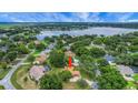 Expansive aerial view showcasing the home's location near a lake and surrounded by lush greenery and mature trees at 10697 Lake Hill Dr, Clermont, FL 34711