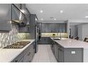 Modern kitchen with stainless steel appliances, mosaic tile backsplash, and spacious island with seating at 1224 Hillcrest View Loop, Apopka, FL 32703