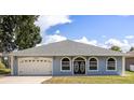 Charming single-story home showcasing a well-maintained lawn, two car garage and inviting arched windows at 13848 Vista Del Lago Blvd, Clermont, FL 34711