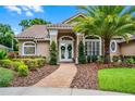 Inviting front entrance featuring double doors with decorative wreaths and a brick walkway surrounded by lush landscaping at 174 Promenade Cir, Lake Mary, FL 32746
