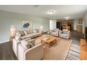 Staged living room featuring neutral furniture, a jute rug, and seamless connection to the kitchen area at 1793 Western Hills Ln # N, Mascotte, FL 34753