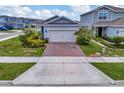 View of the home's exterior, showcasing the landscape and brick paver driveway at 2601 Blowing Breeze Ave, Kissimmee, FL 34744