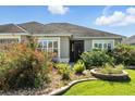 Inviting home featuring decorative shrubbery, a well-manicured lawn, and a dark front door at 2895 Apache Ct, The Villages, FL 32163
