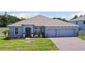 Charming single-story home featuring a well-manicured lawn, brick driveway, and a two-car garage at 5264 Obsidian Gate Dr, Mount Dora, FL 32757