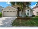 Beautiful home features a two-car garage, mature tree, and a pristine lawn with decorative rocks at 6720 Winder Lynne Ln, Orlando, FL 32819