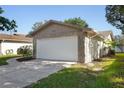 Home's two-car garage featuring stone accents and a well-maintained lawn at 10519 Wyndcliff Dr, Orlando, FL 32817