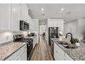 Bright kitchen featuring granite countertops, stainless steel appliances, and white cabinets with modern hardware at 16564 Silversaw Palm Dr, Winter Garden, FL 34787