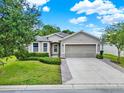 Well-maintained single-Gathering home with a two-car garage, green lawn and mature landscaping at 2216 Sequoia Way, Davenport, FL 33896