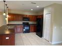 A spacious kitchen featuring tile flooring, dark cabinetry, and black appliances at 2299 Rock Dr, Poinciana, FL 34759