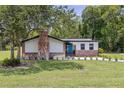 Quaint home boasting a brick chimney, beautiful lawn, and a pop of color with its bright blue door at 608 Cedar Ave, Holly Hill, FL 32117