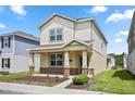 Inviting two-story home featuring a covered porch with stone accents and well-manicured lawn at 6449 Sprucepine Ln, St Cloud, FL 34771
