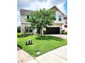 Well-maintained front yard of a two-story home with lush green grass and mature trees, and brick driveway at 813 Marsh Reed Dr, Winter Garden, FL 34787