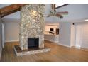 Open-concept living room with a stone fireplace, hardwood floors, and a view of the kitchen at 1102 Winter Springs Blvd, Winter Springs, FL 32708