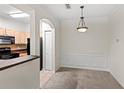 Open dining area with elegant wainscoting and modern light fixture adjacent to a kitchen with black appliances at 12843 Madison Pointe # 208, Orlando, FL 32821
