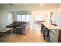Bright open-concept living space featuring tiled floors, a comfortable sectional and access to the patio at 2612 Summer Clouds Way, Kissimmee, FL 34744