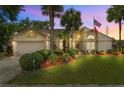 Charming home at dusk featuring a manicured lawn, palm trees, and vibrant landscaping at 5704 Bay Side Dr, Orlando, FL 32819