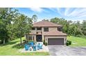 Attractive two-story home with a manicured lawn, a seating area with blue rocking chairs, and an attached garage at 6346 Dallas Blvd, Orlando, FL 32833
