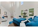 Bright living room with soaring ceilings, large windows, and stylish blue furniture on white tile floors at 9814 Amber Chestnut Way, Winter Garden, FL 34787