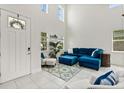 Bright living room with high ceilings, large windows, and stylish blue furniture on white tile floors at 9814 Amber Chestnut Way, Winter Garden, FL 34787
