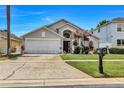 Inviting single-Gathering home featuring a lush lawn, a two-car garage and decorative plants at 1019 Lake Berkley Dr, Kissimmee, FL 34746