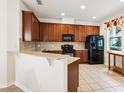 Well-equipped kitchen with wooden cabinets, modern appliances, and tiled floors offers functionality at 12884 Calderdale Ave, Windermere, FL 34786