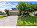 Well-maintained home featuring a brick-paved driveway, lush lawn, mature trees, and a two-car garage at 2850 Spring Heather Pl, Oviedo, FL 32766