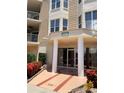 Inviting building entrance with a modern design, complemented by vibrant red flowers at 4628 Harbour Village Blvd # 2308, Ponce Inlet, FL 32127