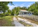 Exterior showcasing the home with a long driveway, white picket fence, and a glimpse of the surrounding yard at 516 Tybee Pl, Orlando, FL 32829
