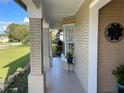 Charming front porch featuring brick columns, tile flooring, and a lovely plant display, offering a welcoming entrance at 1025 Sullivan St, Deltona, FL 32725