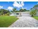 Charming home featuring a brick paver driveway, lush lawn, and four chairs sitting on a white stone garden at 2102 Ivanhoe Rd, Orlando, FL 32804