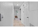 Bright hallway with ceramic tile flooring, featuring white walls, neutral doors, and recessed lighting at 3997 Versailles Dr # 3997F, Orlando, FL 32808