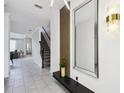 Stylish entryway featuring modern light fixtures, a large mirror, and staircase access at 4367 Rhyme St, Kissimmee, FL 34746
