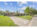 Quaint single-story home with a long driveway, carport, and an 'ACME' sign in the front yard at 5527 Sandalwood Dr, Orlando, FL 32839
