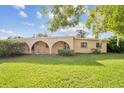 Inviting single-story home featuring a unique arched porch and lush front lawn under a bright sky at 5527 Sandalwood Dr, Orlando, FL 32839