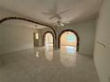 Spacious living room featuring tiled flooring, arched brick openings, and natural light from a window at 5527 Sandalwood Dr, Orlando, FL 32839