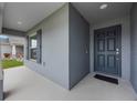 Covered porch with dark gray front door and gray siding, plus a view of manicured lawn at 220 Foxtail Loop, Davenport, FL 33837