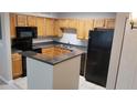 Cozy kitchen with wood cabinets, black appliances and breakfast bar with dark grey countertops at 420 Forestway Cir # 202, Altamonte Springs, FL 32701