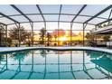 Screened-in pool with sunset views over the lake at 5552 Remsen Cay Ln, Windermere, FL 34786